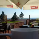 Widok z kawiarni na plaży z widokiem na morze i parasolami z logo Tyskie.