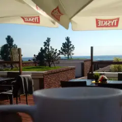 Widok z kawiarni na plaży z widokiem na morze i parasolami z logo Tyskie.